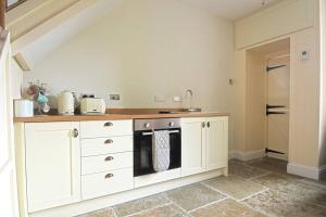 a kitchen with white cabinets and a stove at Coquetdale Cottage in Rothbury, Nr National Park in Rothbury