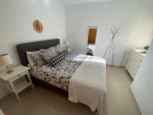 ein weißes Schlafzimmer mit einem Bett und einem Nachttisch in der Unterkunft Casa Milo in Nerja