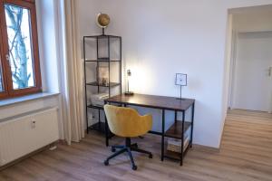 an office with a desk and a yellow chair at Business-Apartment - Citynah, WLAN, Drucker, Netflix & Parken in Chemnitz