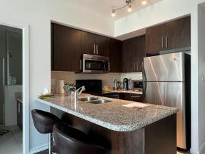 a kitchen with a sink and a refrigerator at Centrally Located - Spacious 2-Bdrm Condo - Next to Scotiabank Arena in Toronto