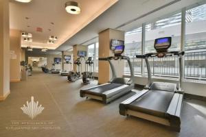 a gym with treadmills and ellipticals in a building at Centrally Located - Spacious 2-Bdrm Condo - Next to Scotiabank Arena in Toronto