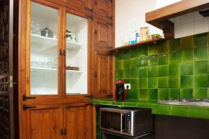 cocina con azulejos verdes y microondas en CanCu Casa en el centro de Sant Feliu de Guíxols en Sant Feliu de Guixols