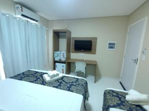 a hotel room with two beds and a television at HOTEL LA SIERRA in Bodoquena