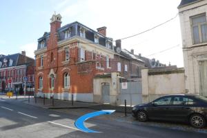 Face à Matisse في Le Cateau: سيارة متوقفة أمام مبنى من الطوب
