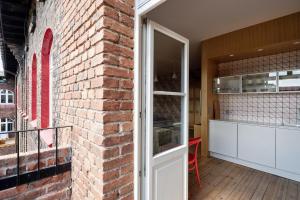 an open door to a brick wall with a kitchen at Kolorowy apartament A9 Katowice Nikiszowiec in Katowice