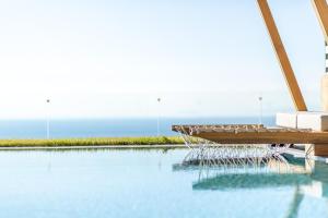 a swimming pool with a bench and the ocean in the background at Mani Theasis in Stoupa
