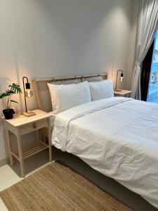 Un dormitorio con una cama blanca y una mesa con una planta en The Beach House, en Mascate