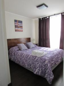Un dormitorio con una cama con sábanas moradas y una ventana en Santiago Central Suites, en Santiago