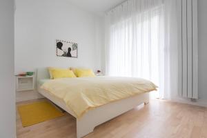 ein weißes Schlafzimmer mit einem großen Bett und gelben Kissen in der Unterkunft 4gZg Apartment in Zagreb