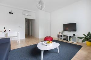ein weißes Wohnzimmer mit einem Tisch und einem TV in der Unterkunft 4gZg Apartment in Zagreb