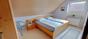 Un pequeño dormitorio con una cama y una silla. en Haus im Wiesengrund, en Esens