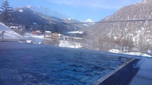 ein Schwimmbad mit schneebedeckten Bergen im Hintergrund in der Unterkunft Hotel Crusch Alba Sta Maria in Sta Maria Val Müstair