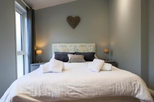 a bedroom with a white bed with a heart on the wall at Beautiful Oak Cabin in Devon Finlake Resort Spa in Chudleigh