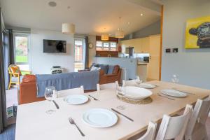 a dining room with a table with plates and wine glasses at Beautiful Oak Cabin in Devon Finlake Resort Spa in Chudleigh