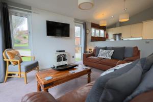 a living room with a couch and a table at Beautiful Oak Cabin in Devon Finlake Resort Spa in Chudleigh