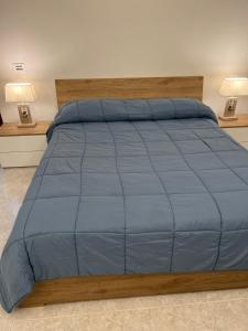 un grande letto con un piumone blu e due lampade di A casa di Frida & Mika - COMODO PUNTO DI SOSTA - a Civita Castellana
