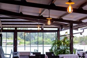 une salle à manger avec des tables blanches, des chaises et des lumières dans l'établissement SAS CLP - La Marina, à Kourou