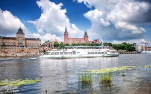 a white boat on the water in front of a building at Szczecin Hanza Tower APARTMENT-BASEN in Szczecin