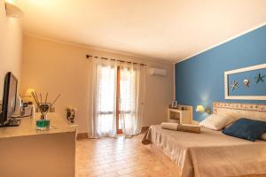 een slaapkamer met blauwe muren en een bed en een televisie bij Relais Isole del Sud in Lampedusa