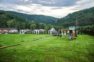 a field with a group of tents and a playground at Green Resort Suncuius in Şuncuiuş