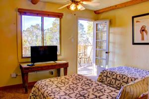 1 dormitorio con 2 camas y escritorio con TV en Beautiful Santa Fe residence blocks from the plaza and close to ski basin, en Santa Fe