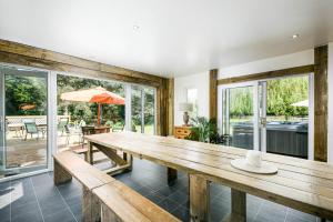 a dining room with a wooden table and windows at Cheerful 7-bedroom house with hot tub sleeps 24 in Iron Acton