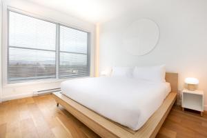 um quarto branco com uma cama grande e uma janela grande em Les Lofts St-François - Par Les Lofts Vieux-Quebec em Cidade de Quebec