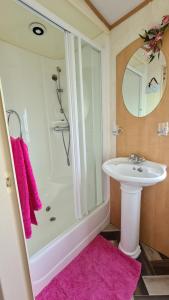 bagno con lavandino, doccia e asciugamani rosa di Caravan 6 berth a Ingoldmells