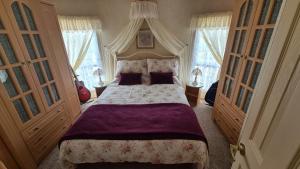 a bedroom with a large bed with purple sheets and windows at Caravan 6 berth in Ingoldmells