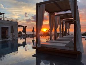 a hotel with a pool with the sunset in the background at Panorama Apartments updated with infinity pool in Agios Nikolaos