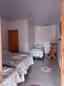a room with two beds and a table in it at Pousada Doce Verde in Ribeirão das Pedras
