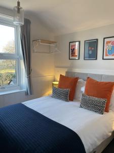 a bed with orange and blue pillows and a window at The Dozy Deer in Windermere