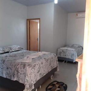 a bedroom with two beds and a mirror at Pousada Doce Verde in Ribeirão das Pedras