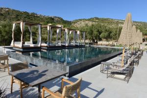 a pool at a resort with tables and chairs at Panorama Apartments updated with infinity pool in Agios Nikolaos
