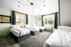 a bedroom with three beds and two windows at Cheerful 7-bedroom house with hot tub sleeps 24 in Iron Acton