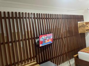 una TV appesa a una parete di legno in una camera da letto di Theo Good Life Hotel a Big Ada