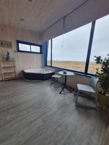 Habitación grande con bañera, mesa y sillas. en Cabaña para 2 con jacuzzi campo mar, en Matanzas
