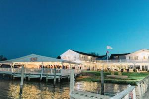 un grupo de personas de pie fuera de un edificio en el agua en Wylder Hotel - Tilghman Island, en St. Michaels