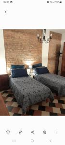 2 letti in una camera da letto con muro di mattoni di Ventisette a Cremona