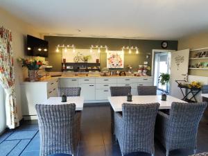 a kitchen with two tables and wicker chairs at B&B De Watering in Lommel