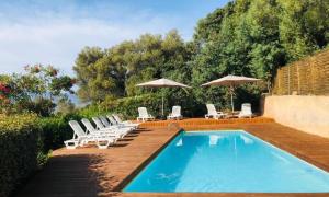 a swimming pool with lounge chairs and umbrellas at Mobilhomme LECCI 3 CHAMBRES AVEC VUE MER EXCEPTIONNELLE in Lumio