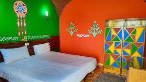 1 dormitorio con 1 cama y una pared colorida en Kato Waidi Nubian Resort en Asuán