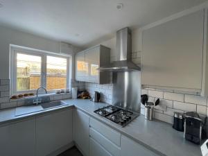 a kitchen with white cabinets and a stove top oven at Rawtenstall bungalow. Steam train passes garden. in Rawtenstall