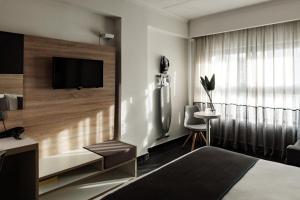 a hotel room with a bed and a tv on a wall at be.HOTEL in St. Julianʼs