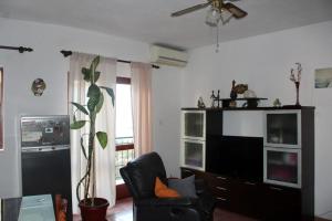 uma sala de estar com uma cadeira preta e uma televisão em Apartment Mirjana em Marina