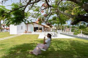 una mujer caminando en el césped delante de una casa en Lilota da Barra - Charme e alto padrão, en Barra de São Miguel