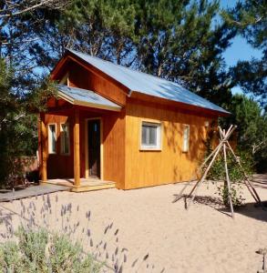 uma pequena cabana de madeira com um alpendre na areia em La Atrevida em José Ignacio