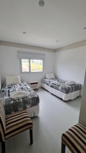 una camera da letto con due letti, una sedia e una finestra di Duplex La Playa a Puerto Madryn