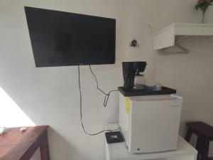 a flat screen tv hanging on a wall above a refrigerator at Squalo's Place in Holbox Island