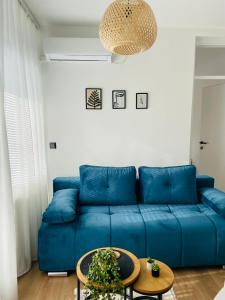 a blue couch in a living room with a table at Comodo apartman Vinkovci in Vinkovci